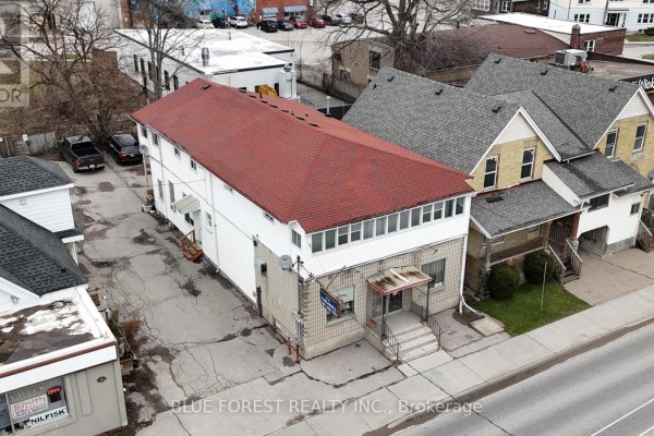 Side aerial view of a commercial building at 452 Horton Street with a red shingle roof and white siding. - 452 Horton Street, London East