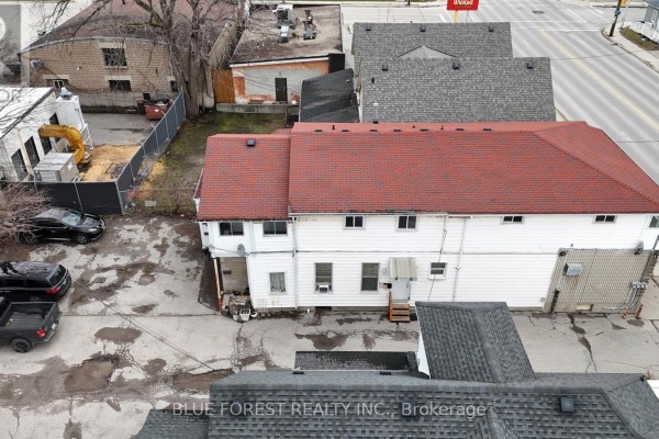 Rear aerial view of a commercial building with white siding, a red shingle roof, and adjacent parking lot. - 452 Horton Street, London East