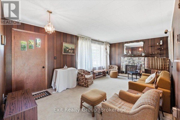 Living room with wood paneling, stone fireplace, and furniture. - 452 Marble Point Road, Marmora And Lake