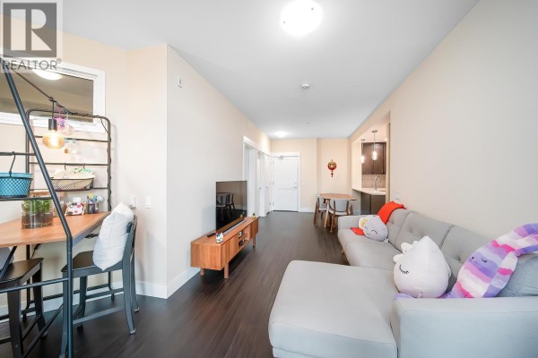 Living area with a grey sectional sofa, TV stand, and a small dining nook near the kitchen. - 4520 2180 Kelly Avenue, Port Coquitlam