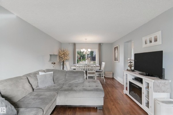 Living room with gray sectional, dining area, and television stand. - 4528 35 Av Nw, Edmonton