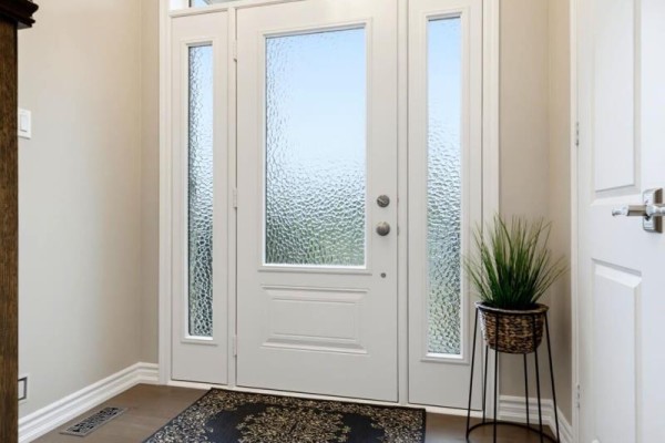 Interior view of a white front door with frosted glass panels and a potted plant. - 453 Kleinburg Summit Way, Vaughan