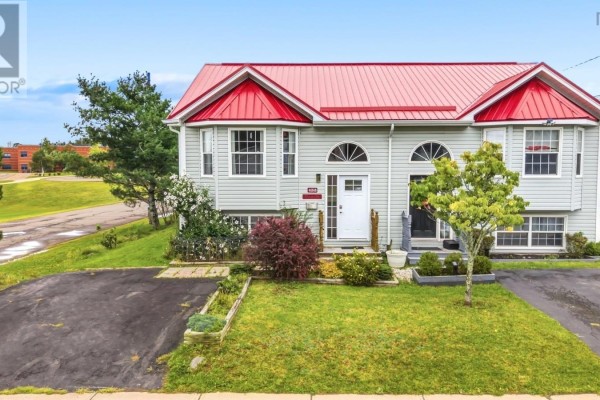 Small bathroom with pink walls, white toilet, wooden vanity, and a pink floral shower curtain. - 453 Young Street, Truro