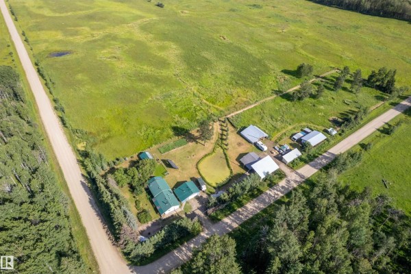 Aerial view of the property showing a house, outbuildings, pond, and fields stretching into the distance. - 453081 Rge Road 75, Rural Wetaskiwin County