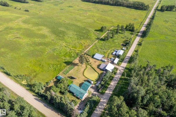 Aerial view of the rural property at 453081 Rge Road 75, featuring a house, outbuildings, and expansive fields. - 453081 Rge Road 75, Rural Wetaskiwin County