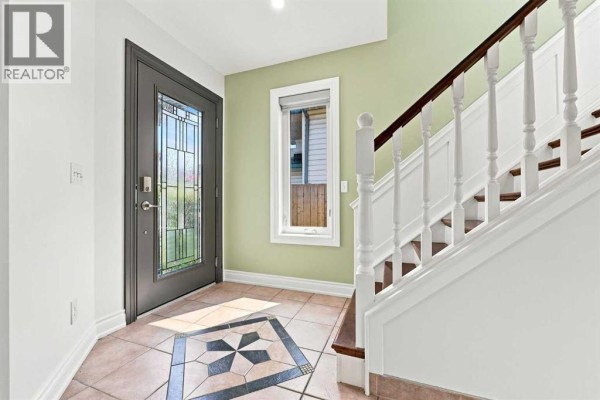 Entranceway with a glass-paned door, tiled floor, and staircase. - 454 Millrise Square Sw, Calgary