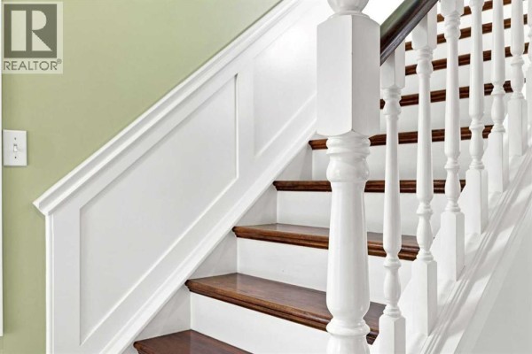 Close-up of a white wooden staircase with dark wood treads and green walls. - 454 Millrise Square Sw, Calgary