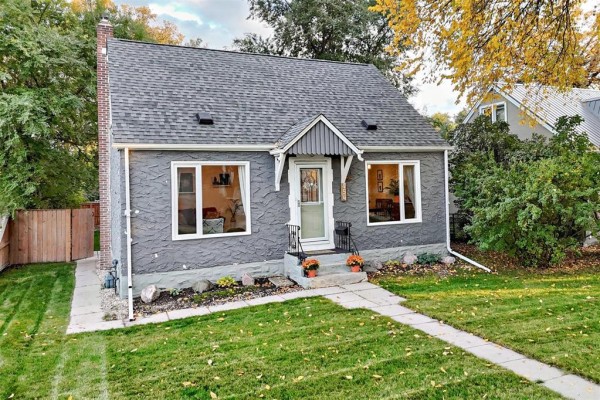 Slightly angled front exterior view of the grey house with a walkway leading to the door. - 454 Montague Avenue, Winnipeg