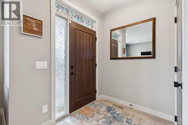 Entrance hallway with a dark wood door, frosted glass sidelight, and a decorative mirror. - 454 Walgrove Way Se, Calgary