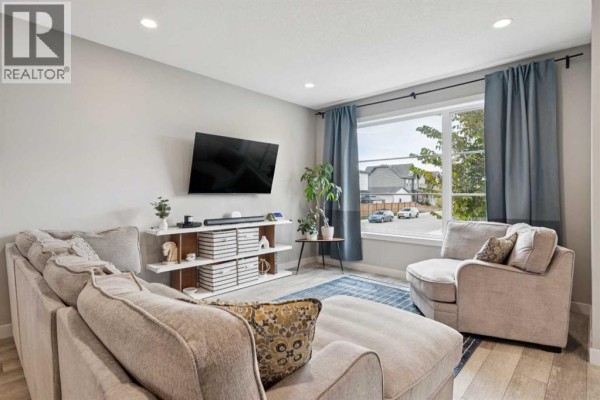 Living room showing a large sectional sofa, television, entertainment unit, and a view of the street. - 454 Walgrove Way Se, Calgary