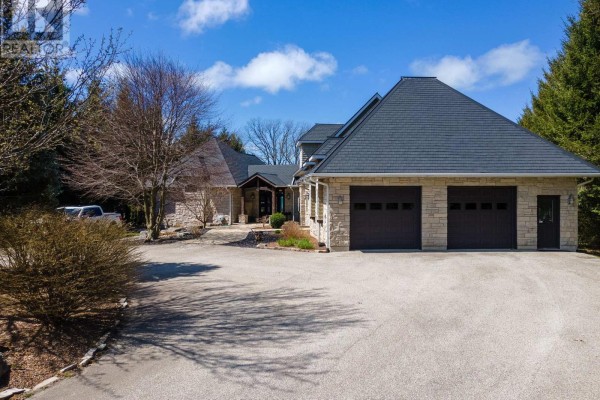 Exterior view of a stone house with a three-car garage and driveway. - 4544 Lakeshore Road, Plympton Wyoming