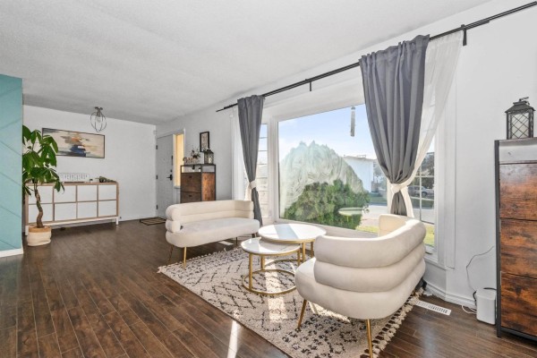 Living room with a large picture window, white furniture, and dark wood floors. - 45492 Spartan Crescent, Chilliwack Proper South, Chilliwack