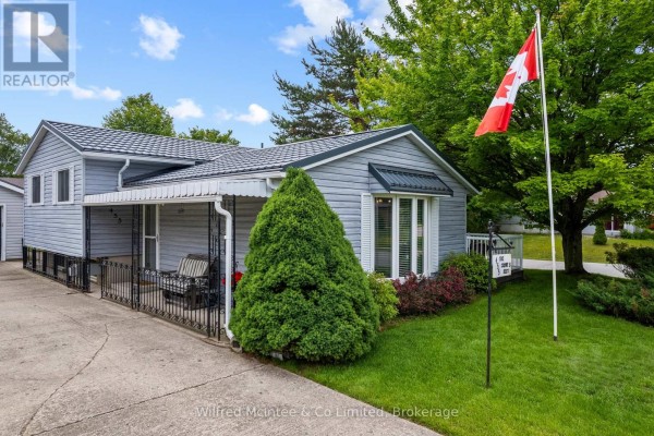 Backyard patio with a table and chairs, adjacent to a grey detached garage and a fenced yard. - 455 Bruce Street, Saugeen Shores