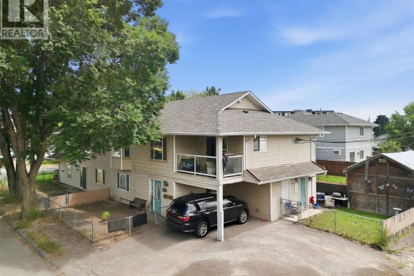 Drone shot of the duplex showing the front and side yards, carport, and a shed. - 455 Campbell Avenue, Kamloops