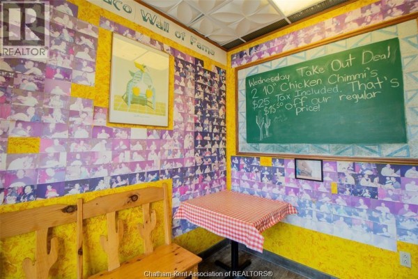 Restaurant seating area with wooden benches, tables, and walls covered in photos. - 455 Grand Avenue East Unit# 11, Chatham