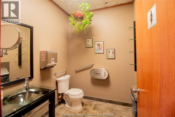 Accessible washroom with toilet, sink, mirror, paper towel dispenser, and grab bars. - 455 Grand Avenue East Unit# 11, Chatham