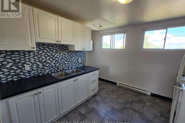 Kitchen with white cabinets, dark countertops, silver backsplash, and tile floor. - 455 King William Street, Hamilton