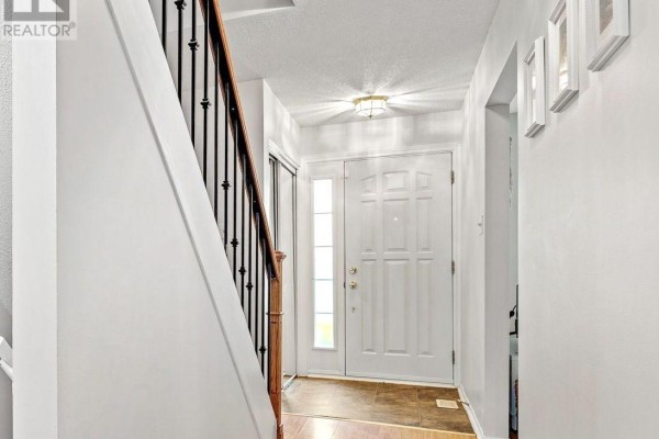 Interior view of a bright entryway with a white front door, tiled floor, and a staircase. - 455 Kintyre Private, Ottawa