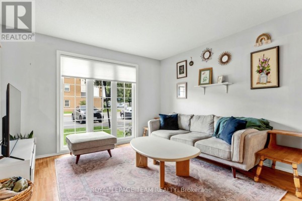 Living room with a sofa, ottoman, coffee table, and framed artwork on a light blue wall. - 455 Kintyre Private, Ottawa