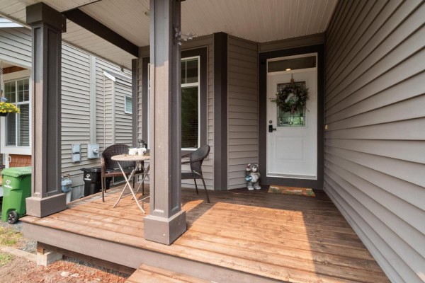 Front entrance with white door, wreath, mat, and porch seating. - 45517 Wells Road, Sardis West Vedder, Chilliwack