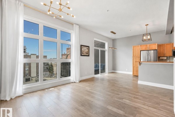 Open concept living area with large windows, kitchen island, and mirrored closet doors. - #456 10403 122 St Nw, Edmonton