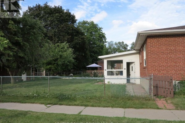 Side view of the house showing a sunroom addition and the backyard fenced area. - 456 Drewry Avenue, Toronto
