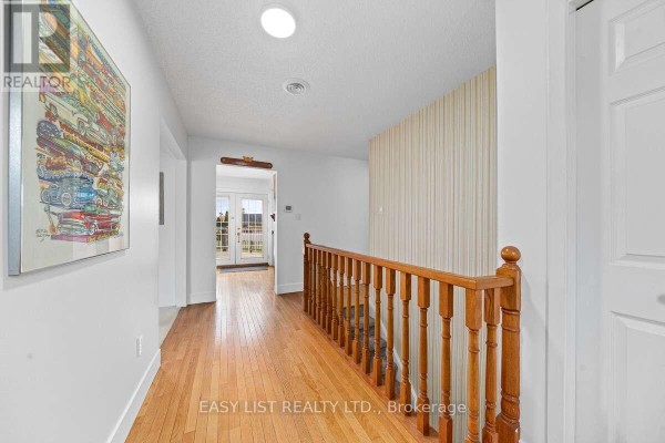 Interior view of a foyer with wooden staircase, hardwood flooring, and natural light. - 456 Old Surrey Lane, Kawartha Lakes