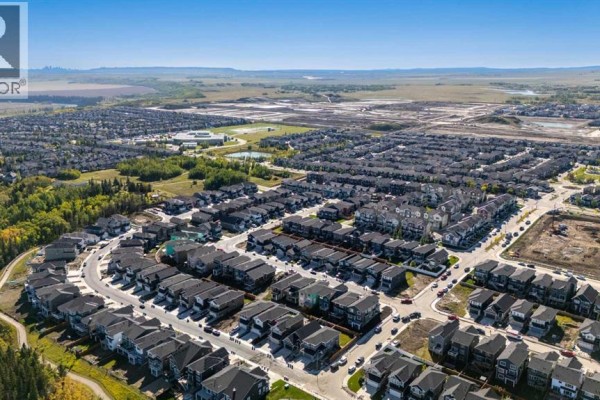 Aerial view of a suburban neighborhood with rows of houses under a bright blue sky. - 456 Rivercrest Road, Cochrane