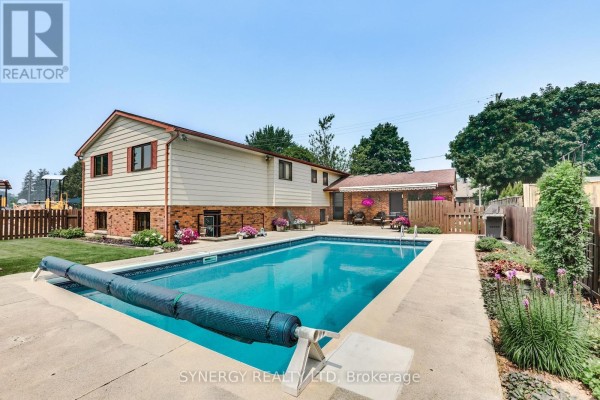 Backyard view of a rectangular in-ground swimming pool with a blue cover. - 456 Saulsbury Street, Strathroy Caradoc