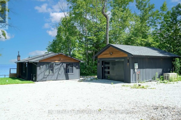 Dark gray wood siding cottage and detached garage with modern glass garage door. - 456 Silver Birch Drive, Tiny