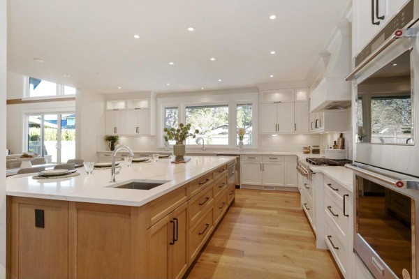 Spacious kitchen with large island, white cabinets, and stainless steel appliances. - 4560 198 Street, Langley