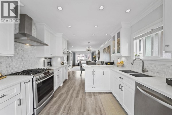Bright living room with a large sectional sofa, entertainment unit, and a window overlooking the street. - 4560 Pender Street, Burnaby