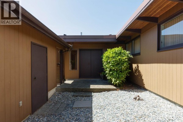 Entrance walkway with gravel, concrete steps, and brown siding. - 4568 Marineview Crescent, North Vancouver