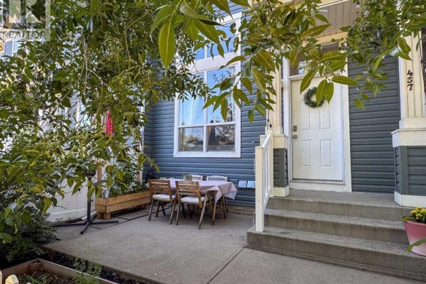 Front entrance with steps, white door, wreath, and outdoor seating area. - 457 Elgin Gardens Se, Calgary