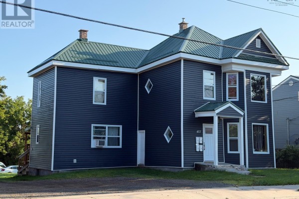 Side exterior view of the dark blue house with a green metal roof and white windows. - 457 Robie Street, Truro