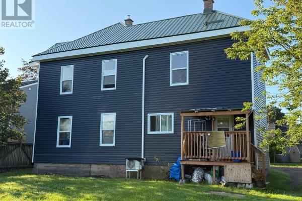 Rear exterior of the multi-family home showing a wooden deck and vinyl siding. - 457 Robie Street, Truro