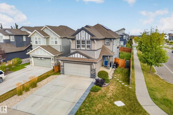 Side aerial view of a grey and white two-story house with a double garage and concrete driveway. - 457 Still Creek Cr Nw, Sherwood Park