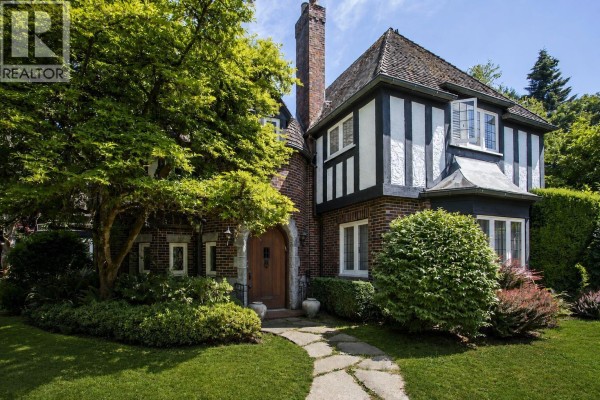Front exterior of a brick and stucco Tudor-style house with a prominent chimney and a stone pathway. - 4576 Connaught Drive, Vancouver