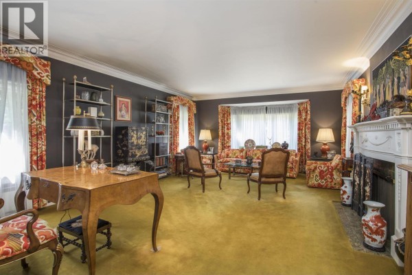 Living room with a yellow carpet, dark grey walls, a fireplace, and a bay window with floral curtains. - 4576 Connaught Drive, Vancouver