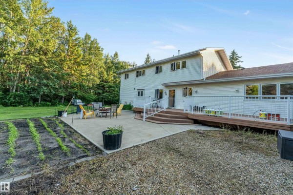 Front entrance of a brick house with a covered porch, white railings, and large bay windows. - #458 23109 Twp Road 514, Rural Strathcona County