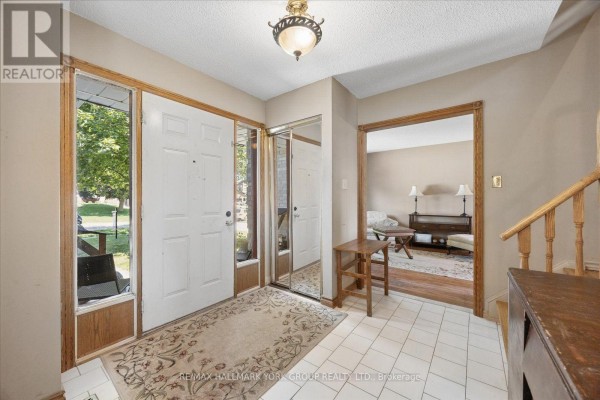 Interior foyer with white tile flooring, double front doors, a mirrored closet, and an archway to a living area. - 458 Chester Avenue, Newmarket