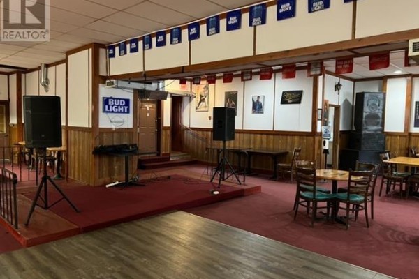 Interior room with a stage, speakers, tables, chairs, and red carpet. - 458 Queen St, Sault Ste  Marie
