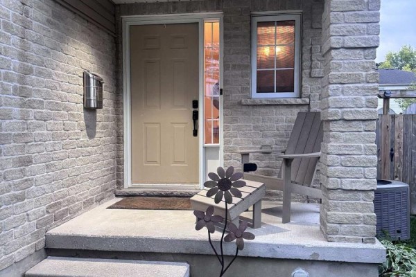 Front door with a window, mail slot, and a chair on the porch. - 459 Albert Street, Stratford