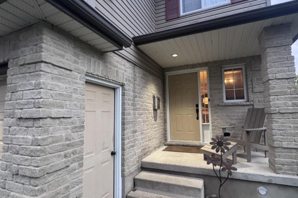 Close-up of the brick exterior, garage, entryway, and porch of a duplex. - 459 Albert Street, Stratford