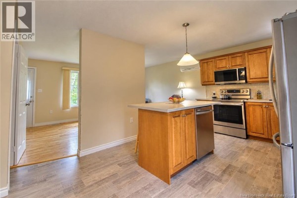 Kitchen with light wood cabinets, stainless steel appliances, and island connecting to living room. - 459 Saint-ignace, Saint Louis De Kent