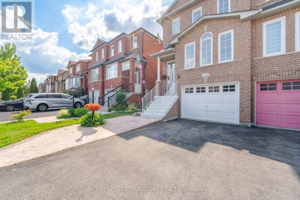 Driveway and lawn leading to a brick semi-detached home with a white garage door. - 459 Wildgrass Road, Mississauga