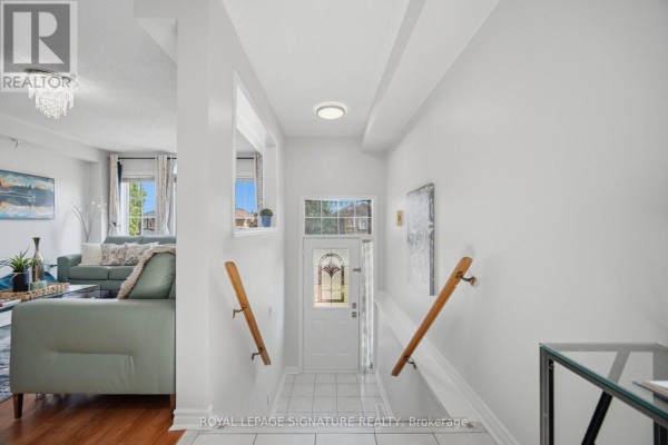 Interior entryway with white tile floor, white walls, and wood handrails on stairs. - 459 Wildgrass Road, Mississauga