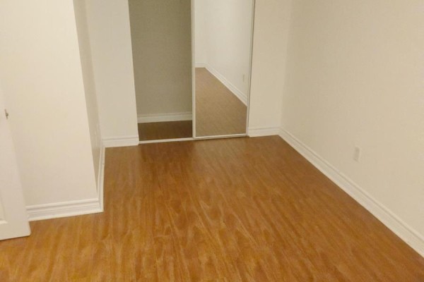 Bedroom area with wood laminate flooring, white walls, and a mirrored closet. - 4594 Bismark Crescent, Mississauga