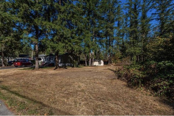 A wide grassy lot with trees and a parked car next to a small dwelling. - 45981 Linzey Road, Cultus Lake East, Cultus Lake