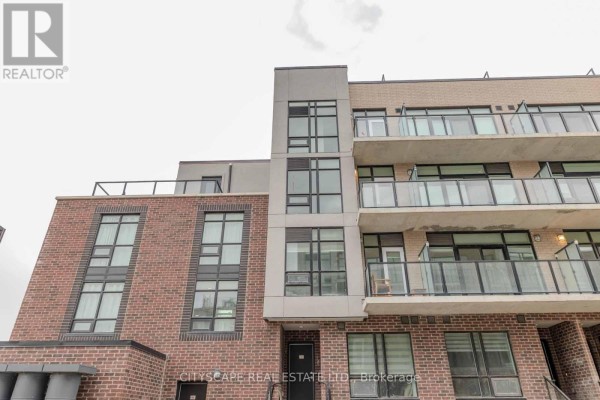 Low-angle view of the multi-story townhouse building with brick and concrete exterior. - 46 - 871 Sheppard Avenue W, Toronto